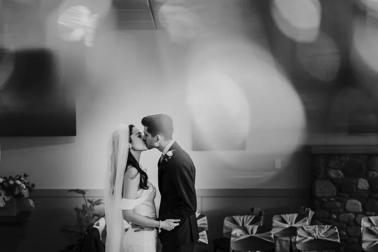 Black-and-white photograph of newlyweds kissing
