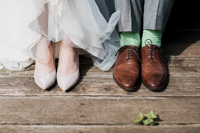 Bridal shoes beside the groom's wedding shoes
