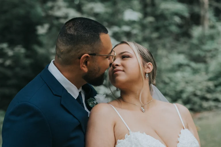 Bride and groom embracing beneath trees
