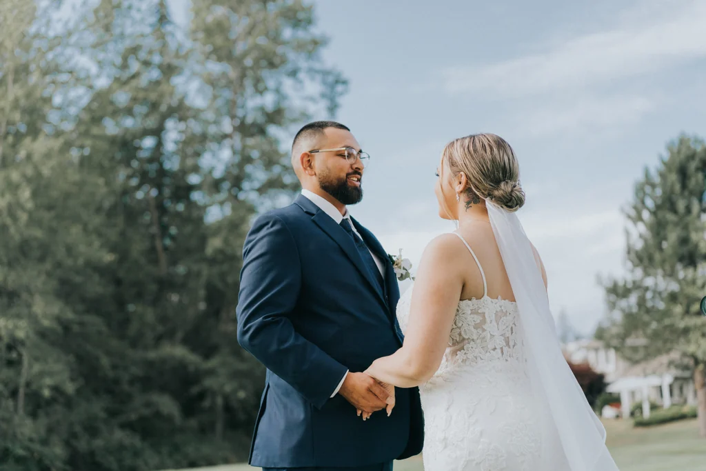 Bride and groom holding hands beside a garden