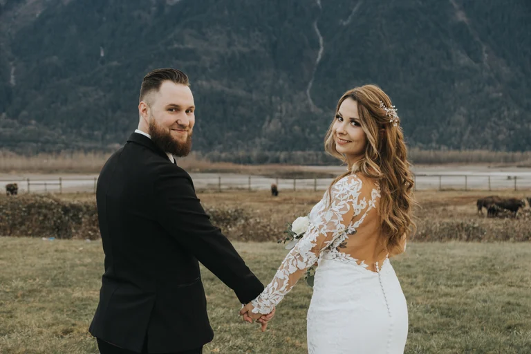 Bride and groom holding hands beside a mountain landscape