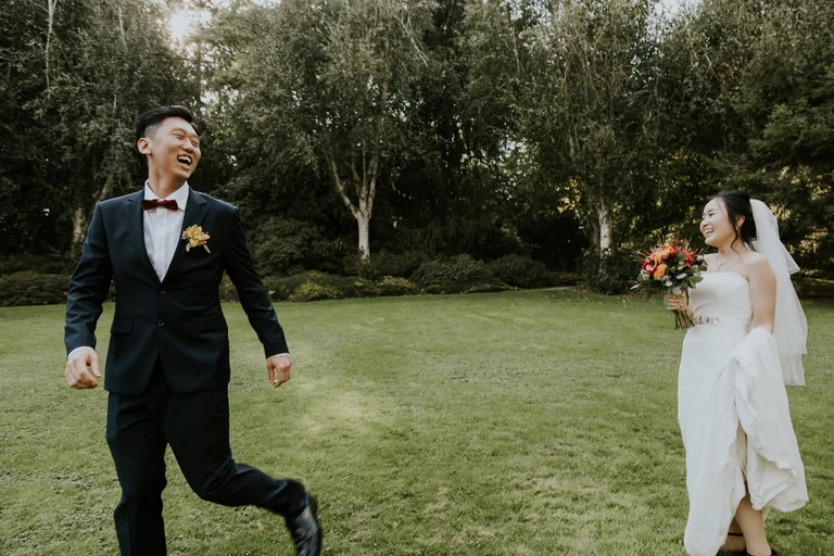 Bride and groom holding hands on a lawn