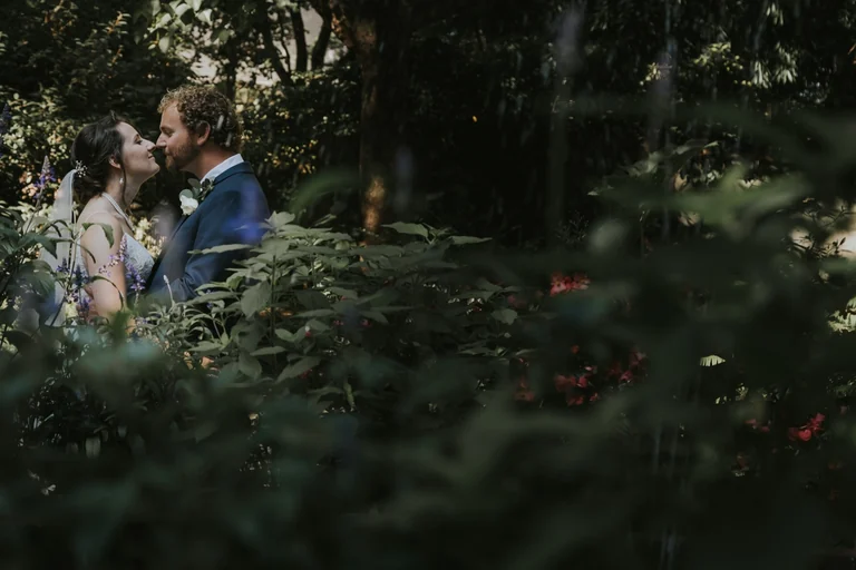 Bride and groom posing among garden flowers