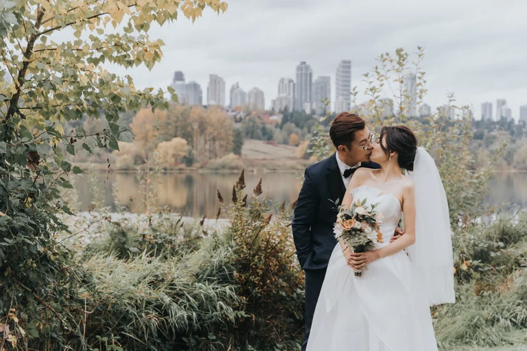 Bride and groom posing with a city skyline in the background