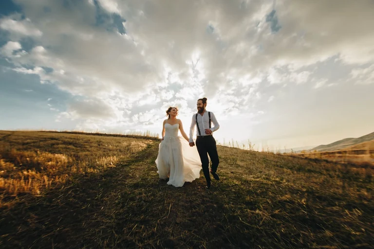 Bride and groom walking beneath a dramatic sky