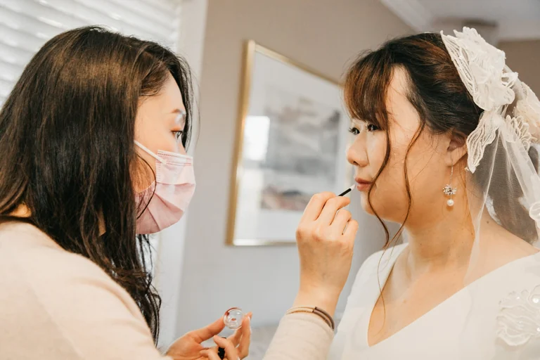 Bride applying makeup while looking in a mirror