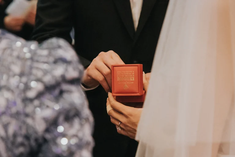 Bride holding a red wedding gift box beside the groom