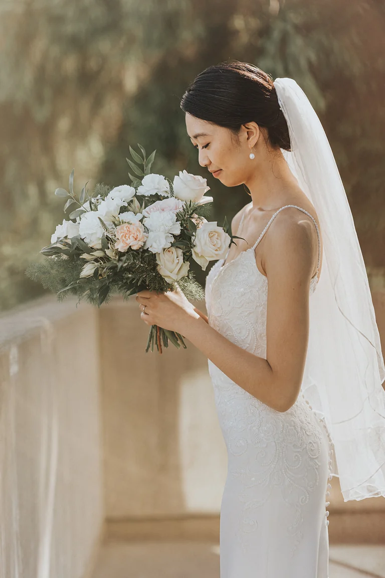 Bride holding her bouquet beside a window