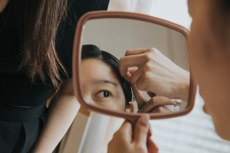 Bride looking into a handheld mirror