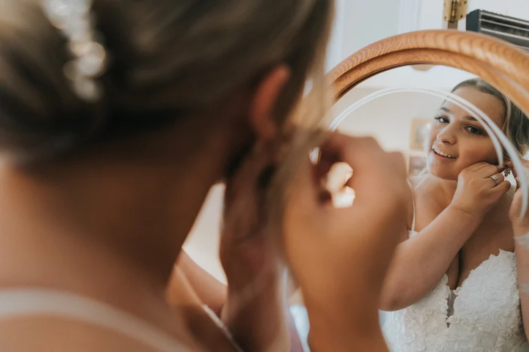 Bride looking into a mirror while getting ready
