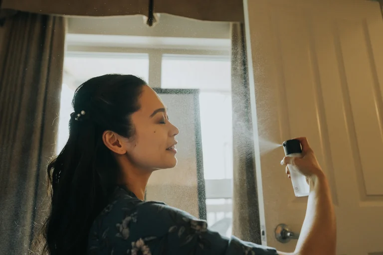 Bride putting on an earring beside a window