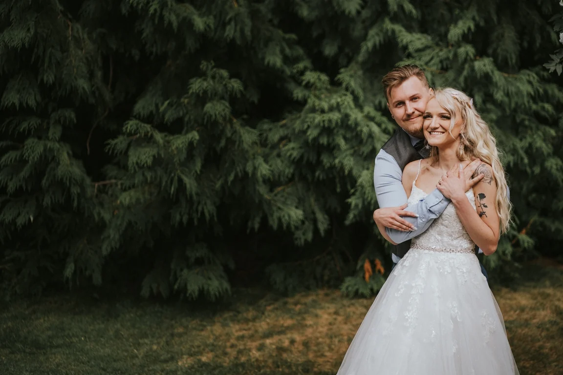 Bride smiling as the groom embraces her from behind