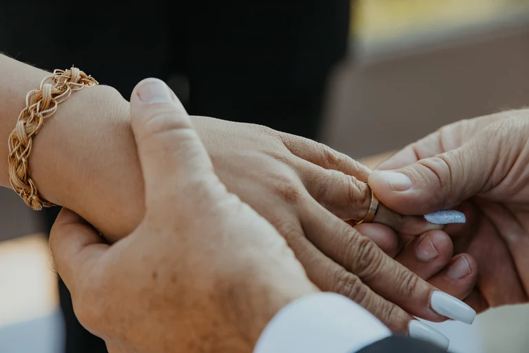 Close-up of a couple holding hands and wedding rings