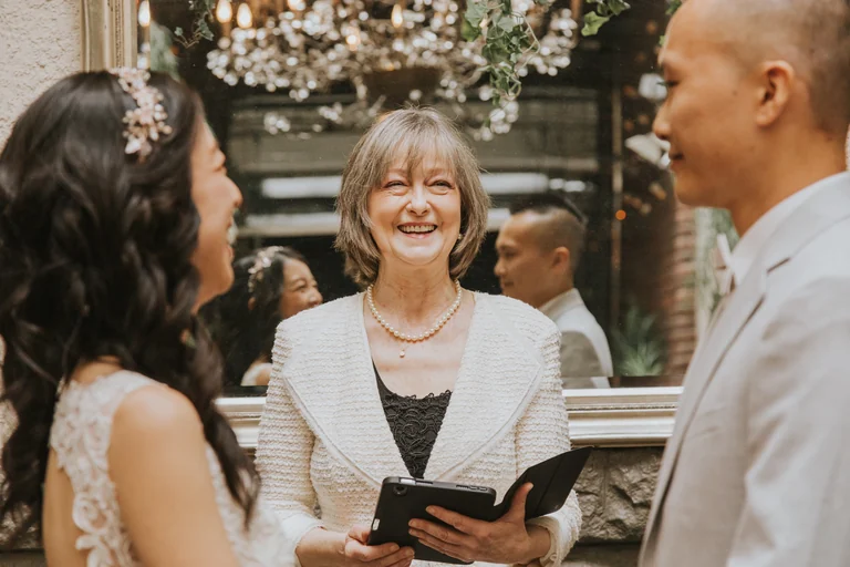 Couple greeting a smiling wedding guest