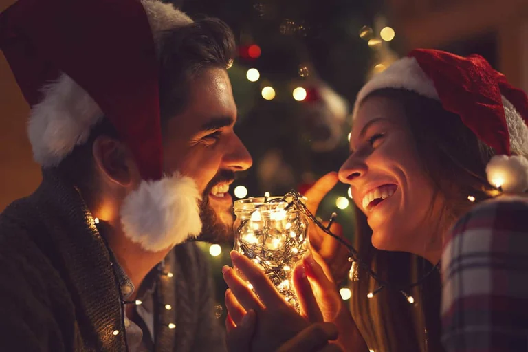 Couple smiling beside festive lights