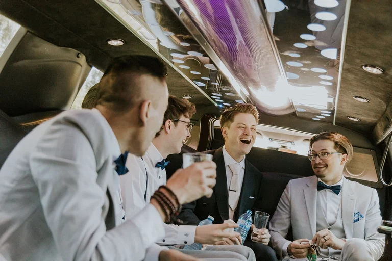 Groom celebrating with friends inside a limousine