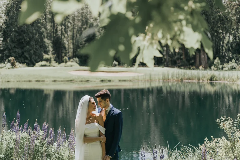 Newlyweds embracing beside a calm lake