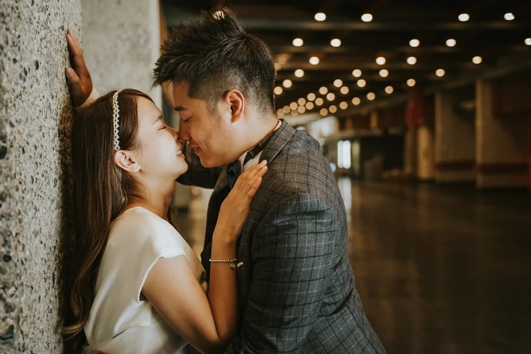 Newlyweds kissing beneath string lights