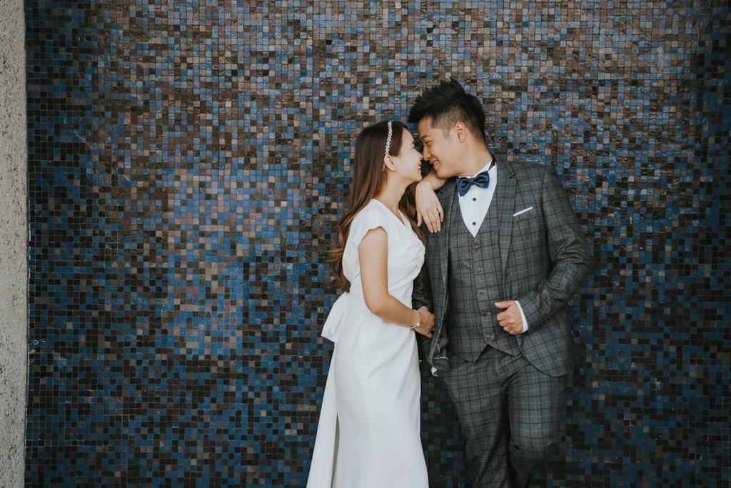 Newlyweds posing against a patterned wall