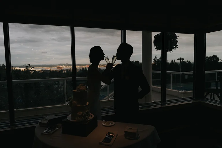 Newlyweds silhouetted beside reception windows