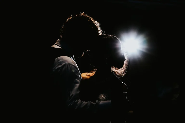 Silhouette of newlyweds dancing beneath a spotlight
