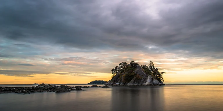 Small island beside the water at sunset
