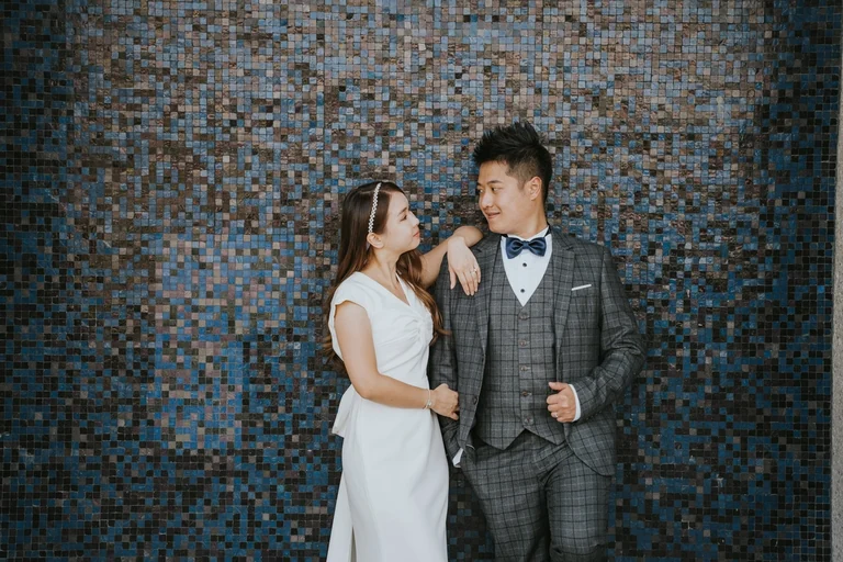 Wedding couple posing against a patterned wall