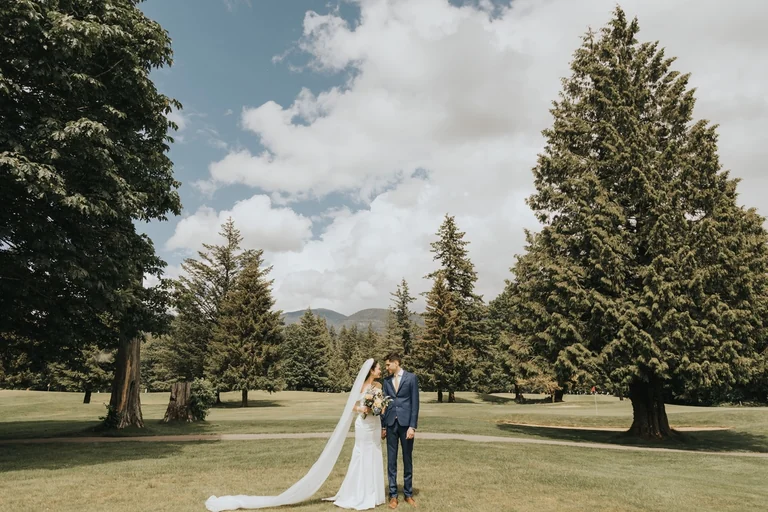 Wedding couple standing on a lawn surrounded by trees