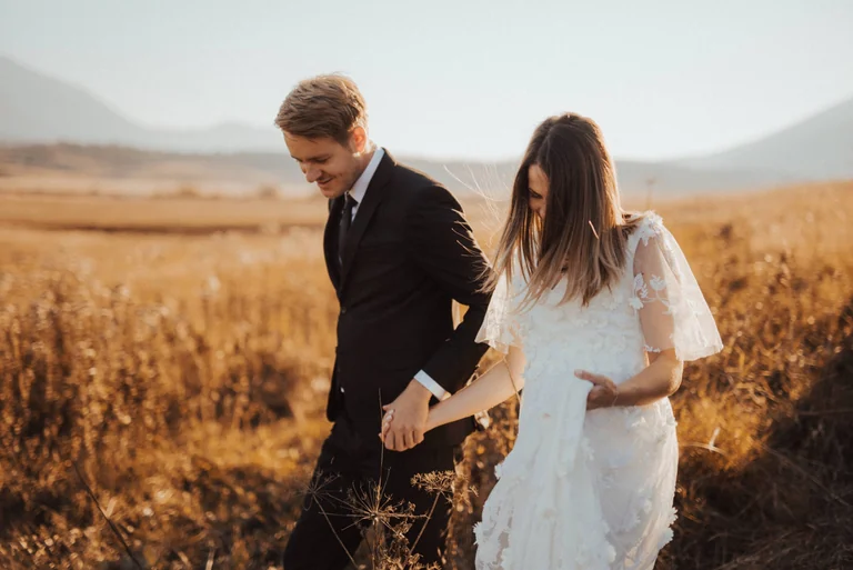 Wedding couple walking through golden grass
