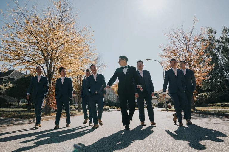 Wedding party standing outdoors in dark suits