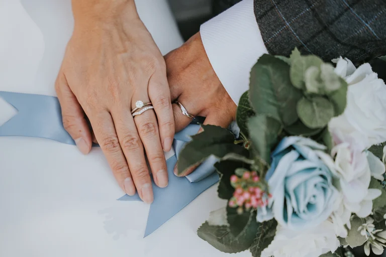 Wedding rings and bouquet beside the groom's suit